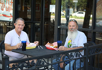 Older men eating together at an outside table
